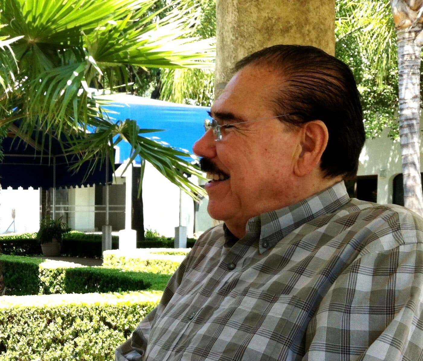 Fidel Chávez Pérez sonriendo de perfil en un jardín
