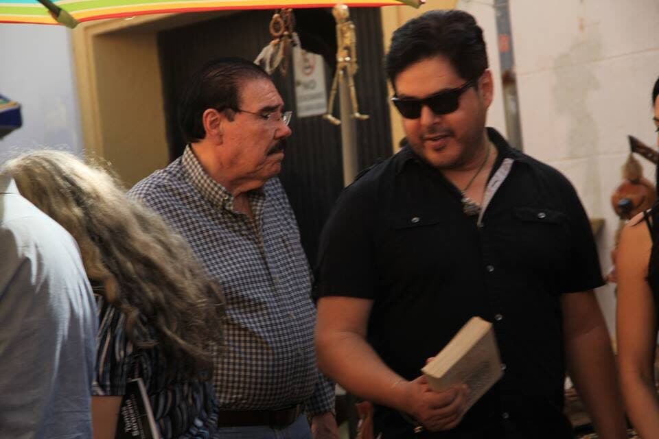 Fidel Chávez Pérez conversando con otro asistente durante un encuentro