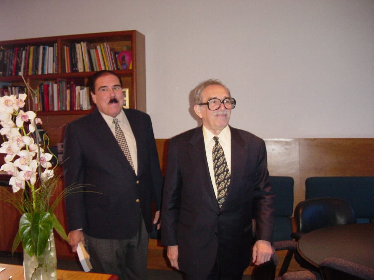 Fidel Chávez Pérez junto a otro escritor frente a una biblioteca