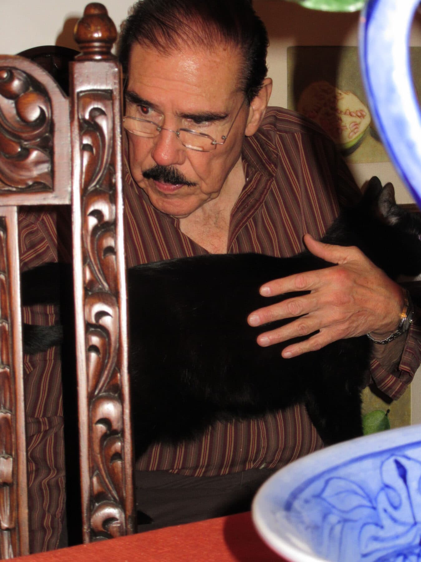 Fidel Chávez Pérez sentado y acariciando un gato
