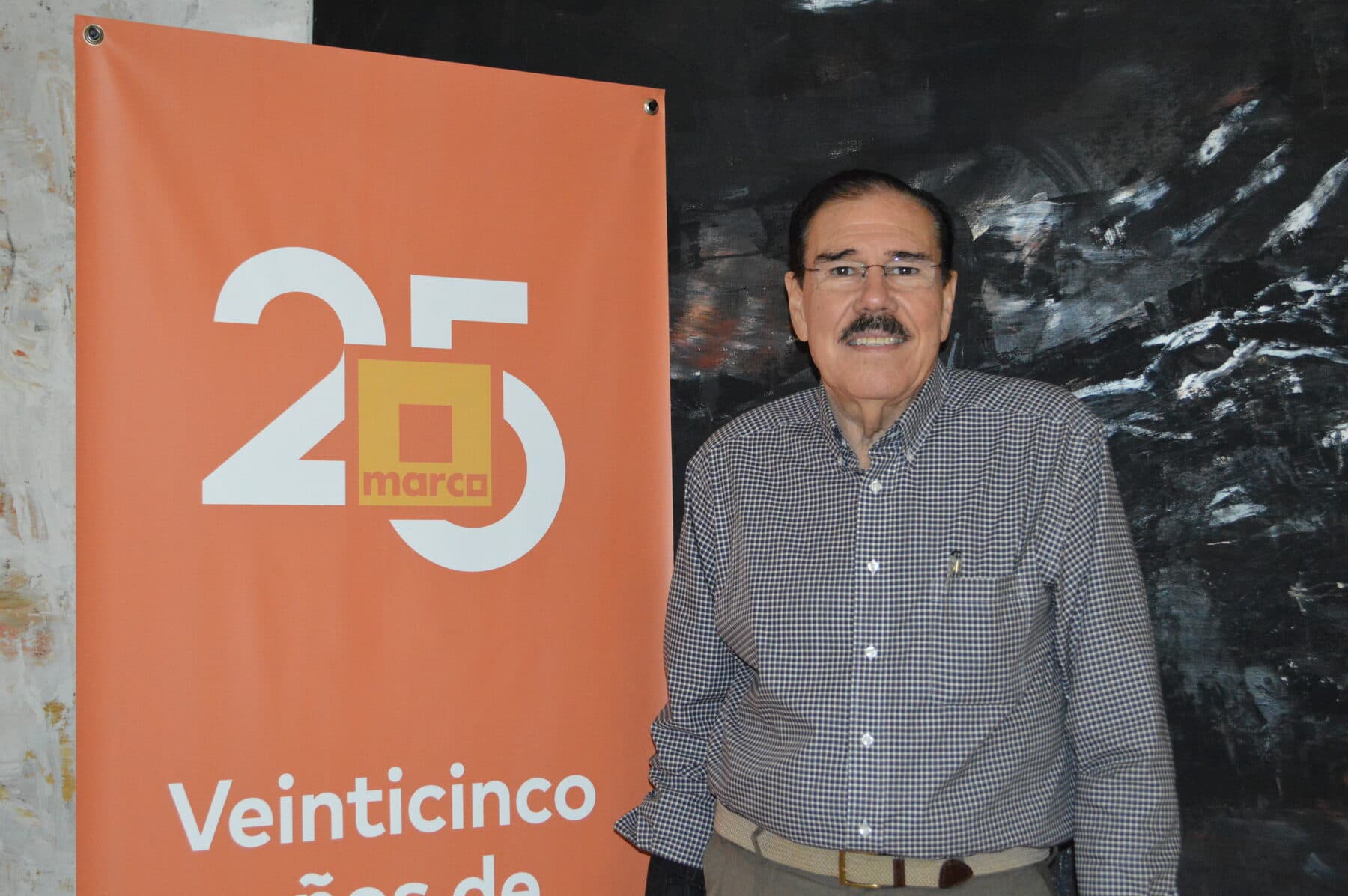 Fidel Chávez Pérez junto al distintivo del aniversario 25 de MARCO